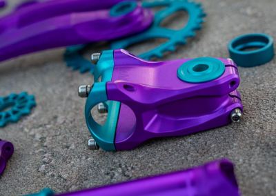 Custom bike part anodizing purple stem with turquoise face plate